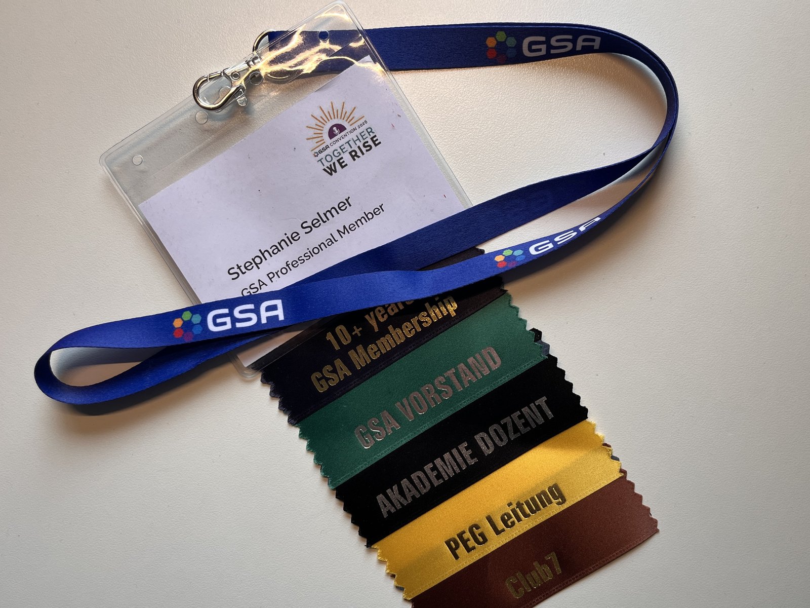 Stephanie Selmer's name badge on a blue GSA lanyard, below it the ribbons for membership, board, academy lecturer, PEG lead and Club7